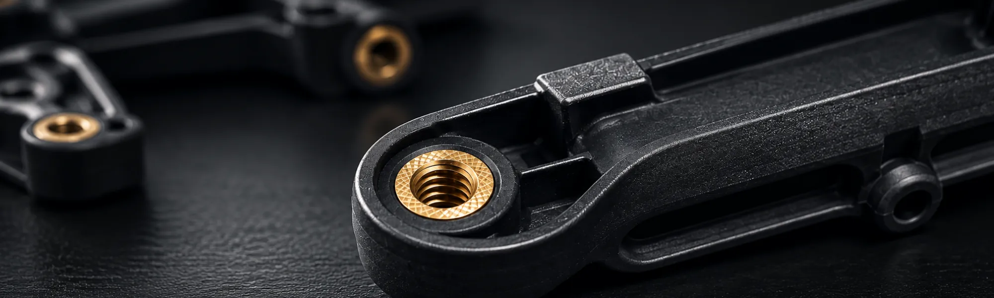 Black moulded component with an integrated brass threaded insert.